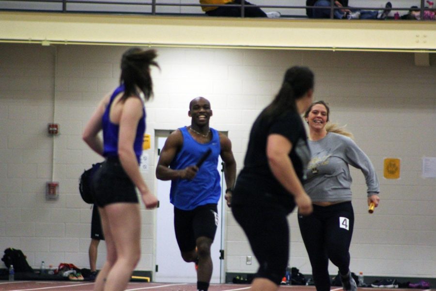 Track alums Dominique Samuel (left) and Lachel Milander (right) race to make the handoff to Lexi Guhl (left) and Carly Fehringer (right) in the alumni 4x160 race during Wayne’s home track meet Jan. 30. 