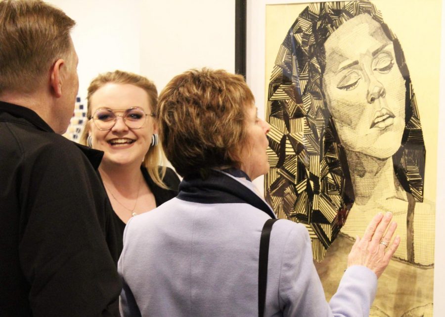 Senior Elley Coffin speaks to spectators during opening night of the senior art exhibit. Coffin is one of seven graduating art students displaying work in the show. 