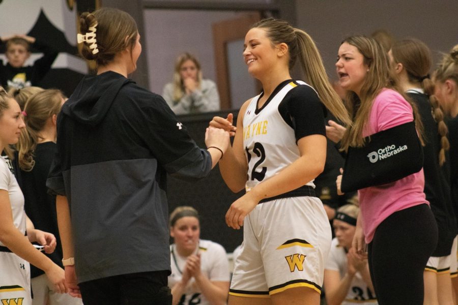 Senior Ashley Gustavson fist-bumps sophomore Tate Norblade as Gustavson is introduced in the Wildcat’s starting lineup.