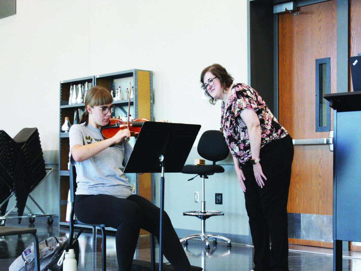 WSC student Abigail Hasemann, left, learns about her instrument from the new strings professor, Kelly Coslet, right. Photo by Kaitlyn Bengston.