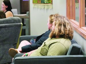 WSC senior and PRIDE club president Kaitlyn Michaelson, left, reads off the powerpoint and shares information about pride flags while WSC junior Adeline Riedmann, middle, and her partner, right, listen. Photo by Mallorie Black. 